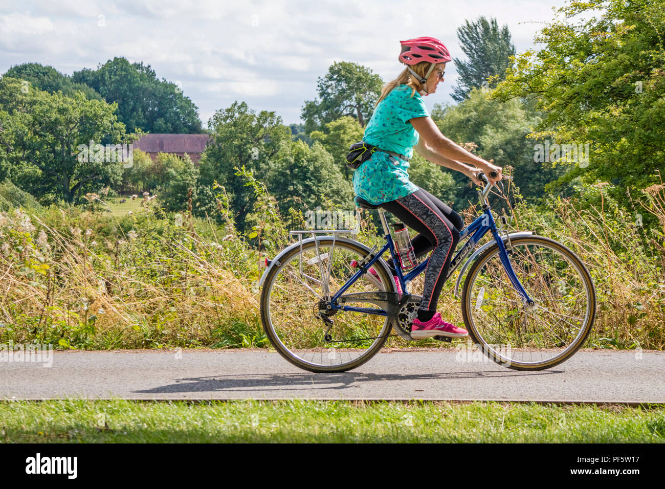 Middle aged lady cycling on a canal towpath, England, UK Stock Photo