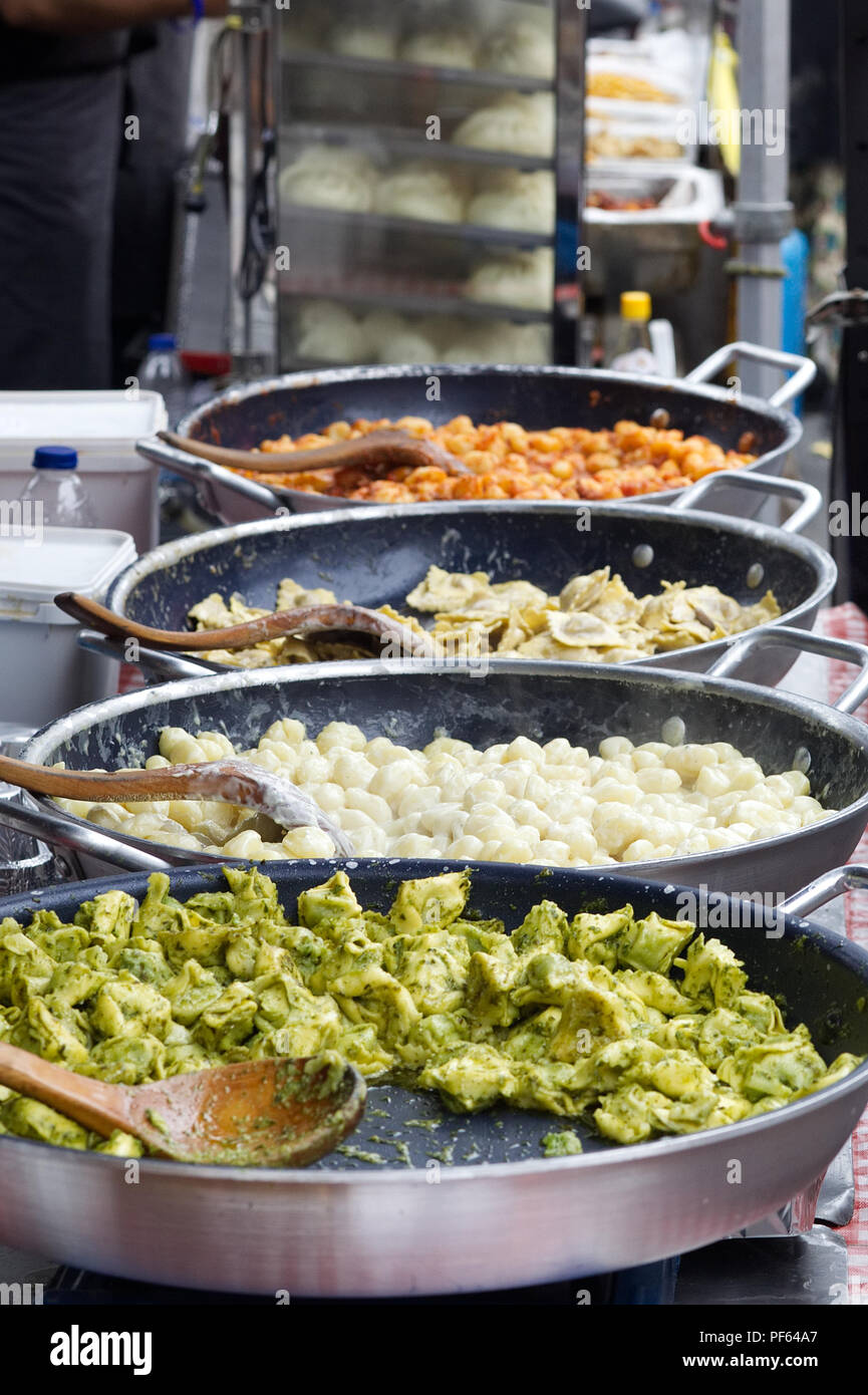 pasta dishes cooking on a market stall. Stock Photo