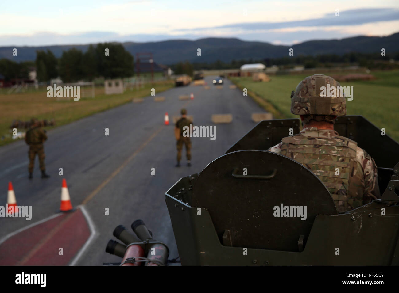 A British Royal Marine observes Norwegian soldiers manning a checkpoint a multinational law enforcement exercise in Vaernes Garnison, Norway, Aug. 14, 2018. Service members practiced vehicle control and entry control point procedures used to identify and search vehicles and personnel entering a military installation. The training, conducted by U.S. Marines with Marine Rotational Force-Europe 18.1, taught American, Norwegian and British military members how to properly set up and execute the checkpoints. (U.S. Marine Corps photo by Cpl. Gloria Lepko/Released) Stock Photo