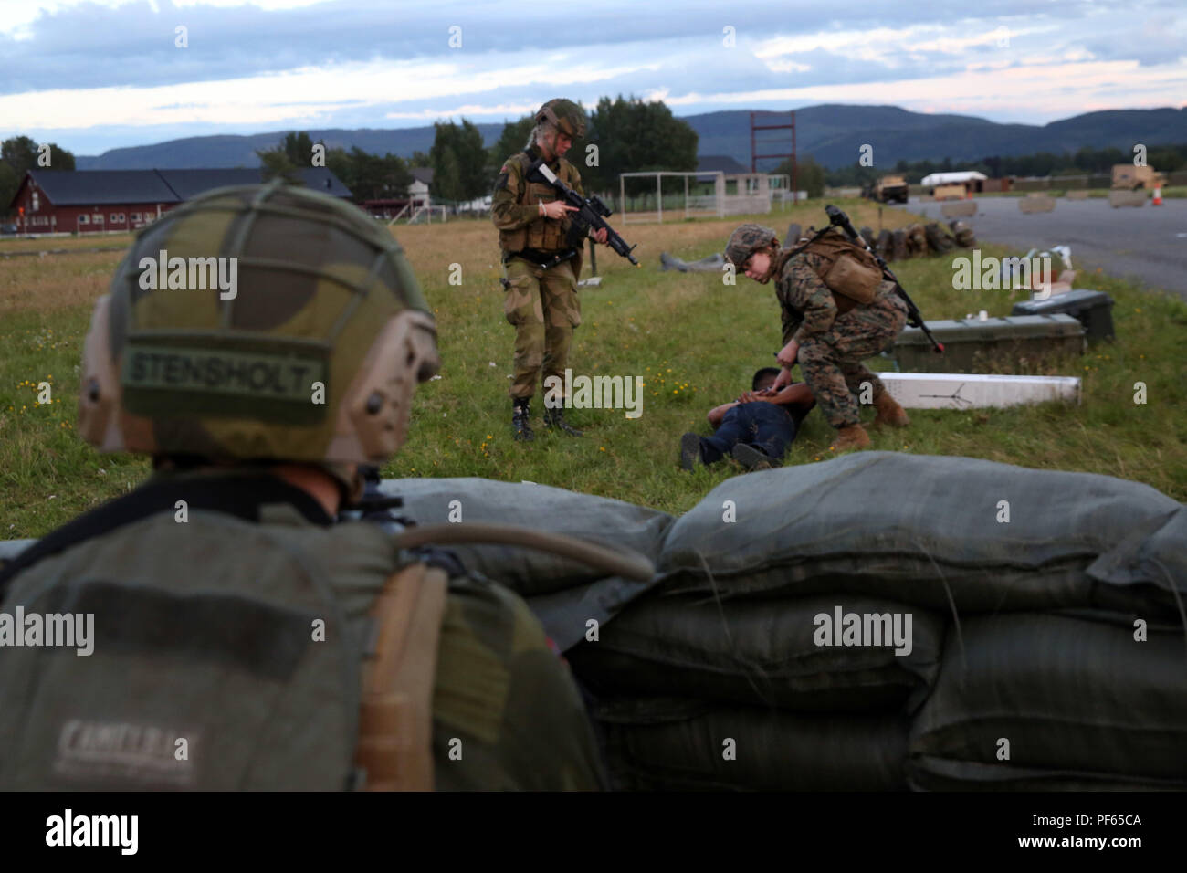 U.S. Marines with Marine Rotational Force-Europe 18.1 detain an uncooperative role-player during a multinational law enforcement exercise in Vaernes Garnison, Norway, Aug. 14, 2018. Service members practiced vehicle control and entry control point procedures used to identify and search vehicles and personnel entering a military installation. The training, conducted by U.S. Marines with Marine Rotational Force-Europe 18.1, taught American, Norwegian and British military members how to properly set up and execute the checkpoints. (U.S. Marine Corps photo by Cpl. Gloria Lepko/Released) Stock Photo