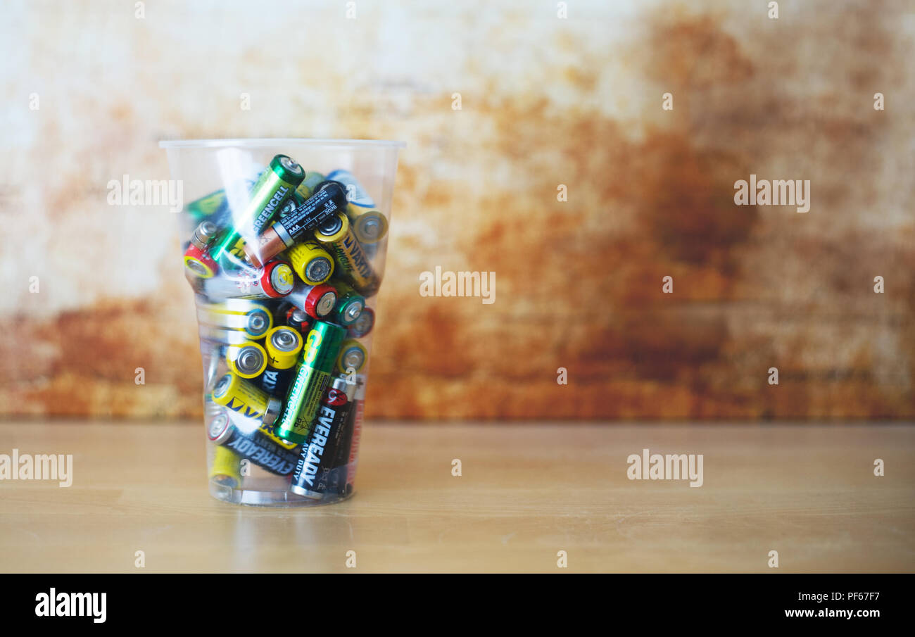 Old Empty Non Rechargeable Batteries Pilled up in Plastic Cup. Blurred Abstract Background. Very Low depth of the Field. Stock Photo