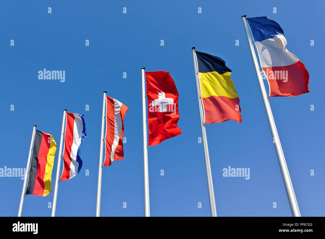 The national flags of Germany, the Netherlands, Austria, Switzerland, Belgium and France flying in front of a blue sky Stock Photo