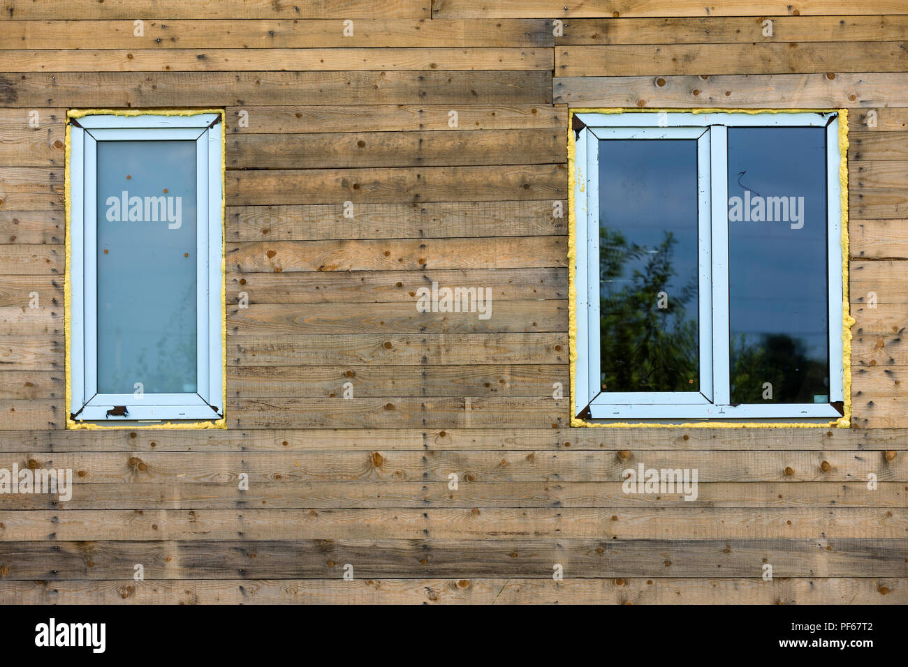 Closeup detail of new narrow plastic vinyl windows installed in house wall of brown natural