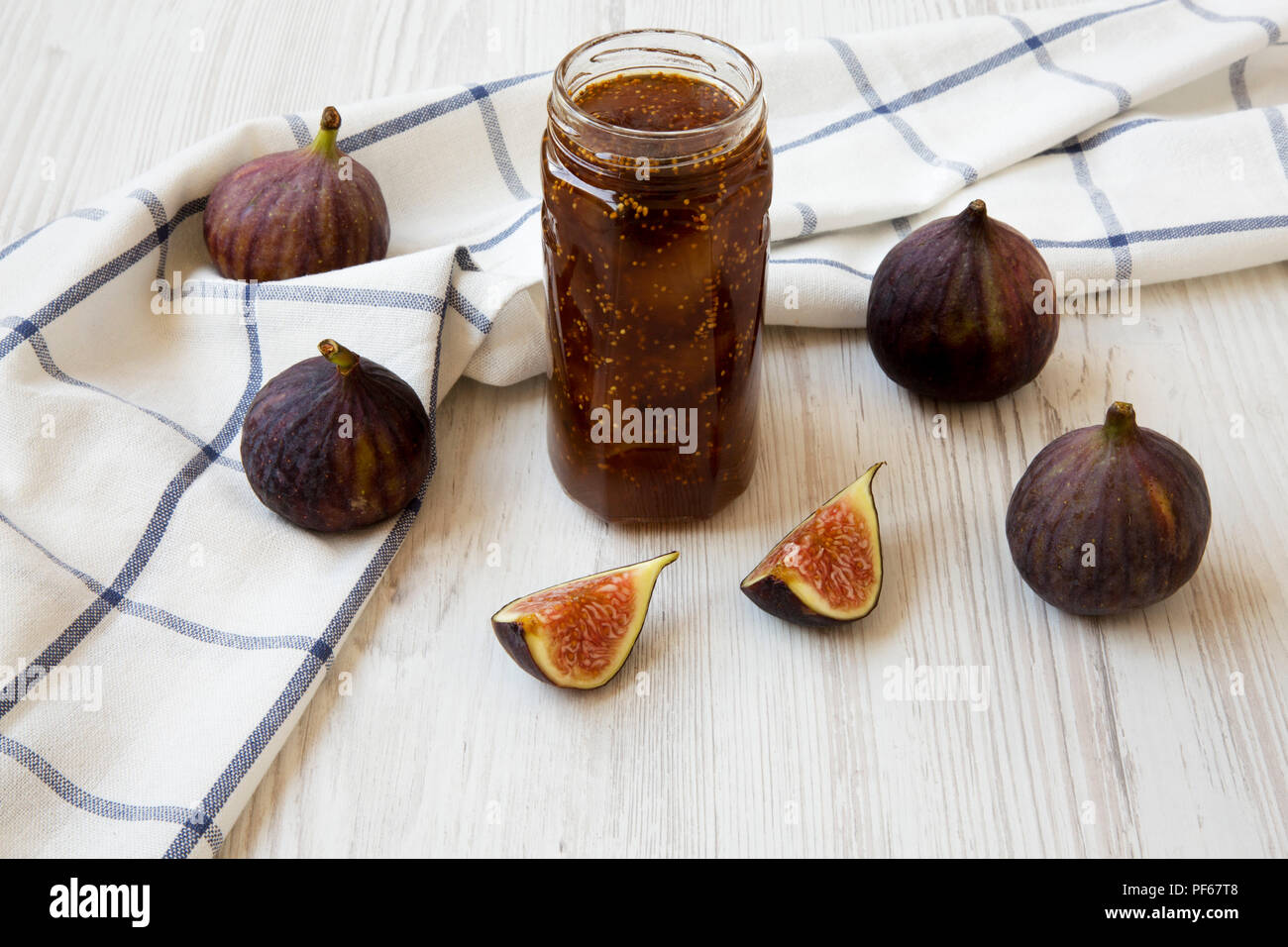 Glass jar of fig jam and fresh figs on white wooden table, side view. Close-up. Stock Photo