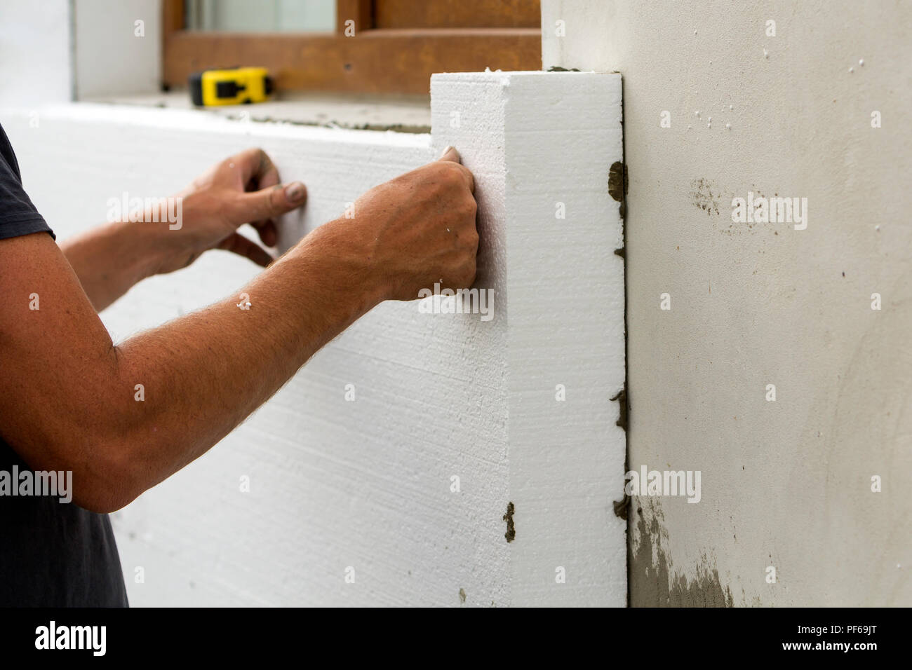 Worker hands installing white rigid polyurethane foam sheet on