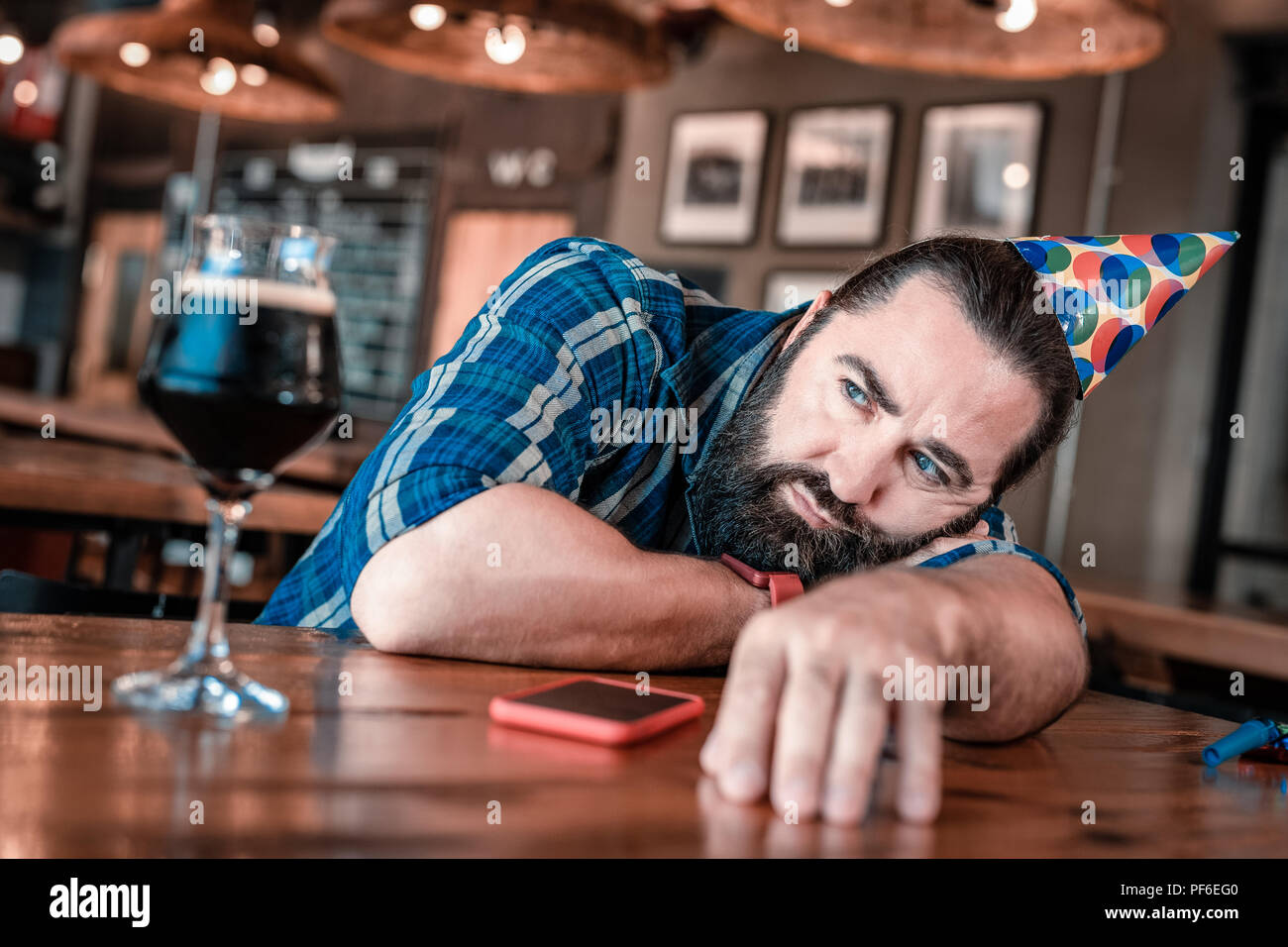 Blue-eyed man feeling unemotional while waiting for his guests on birthday Stock Photo