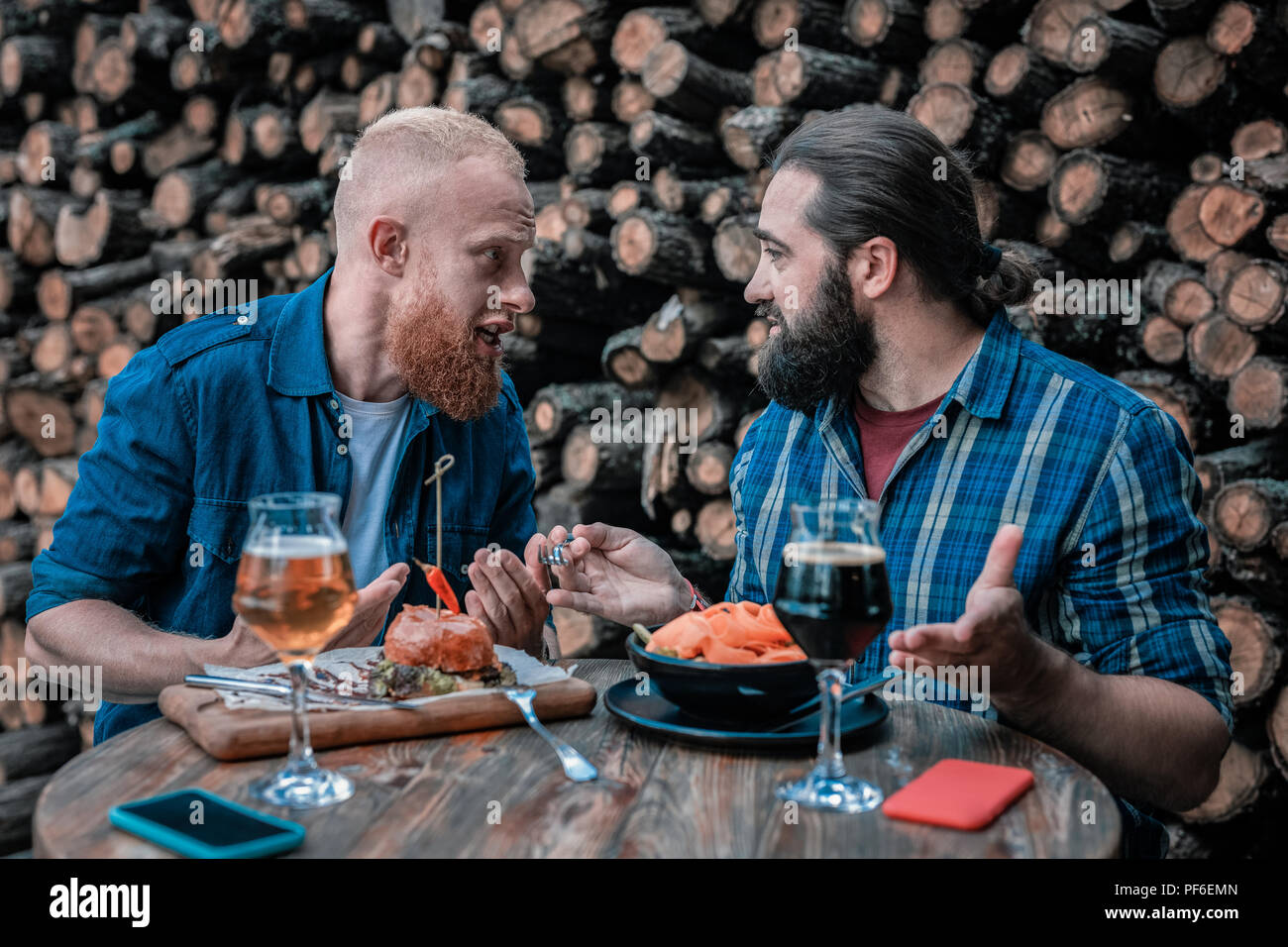 Two bearded men speaking about something while drinking beer Stock Photo
