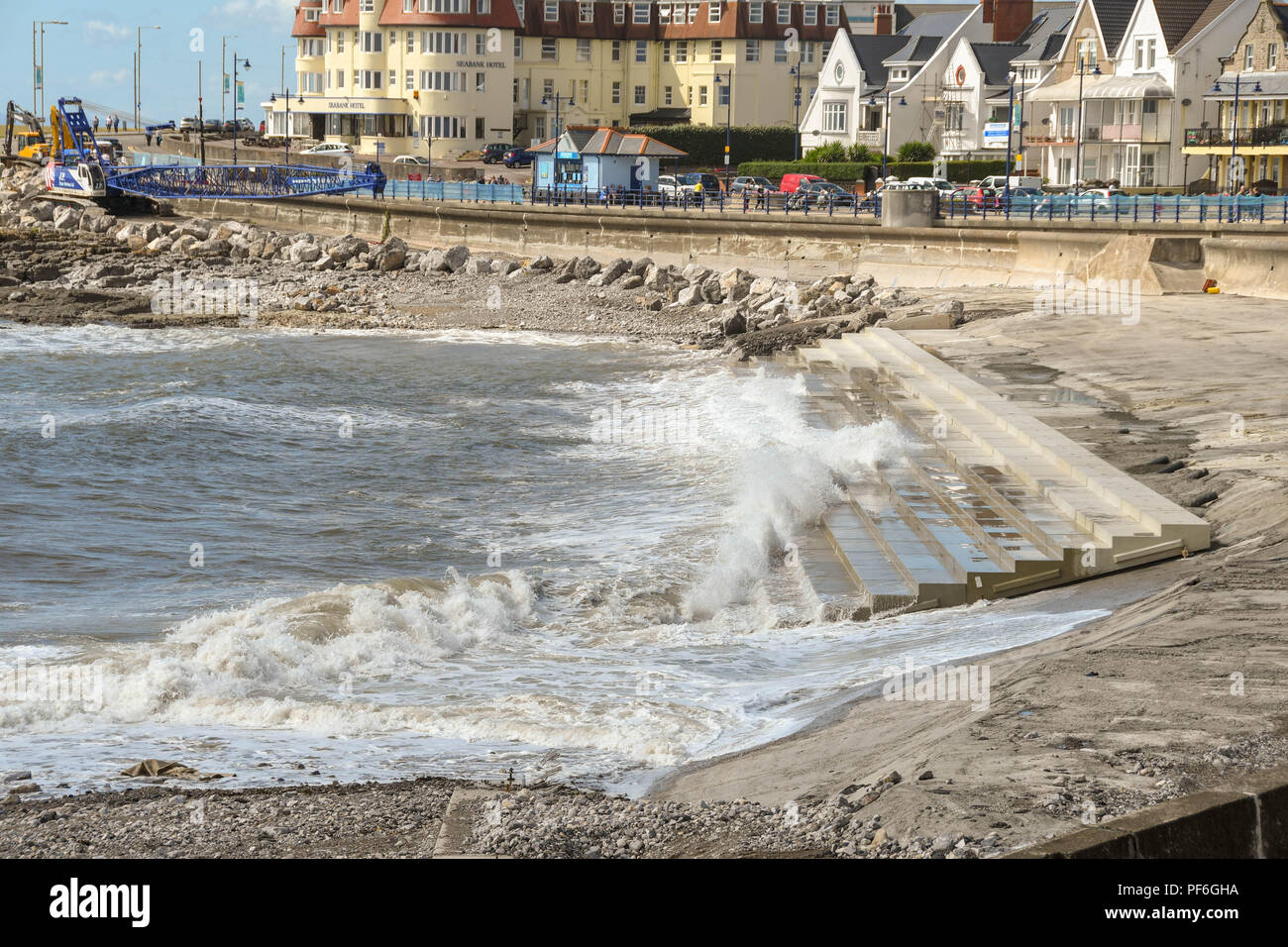 Incoming tide with waves on the seafront in Porthcawl. Wales. The concrete steps are part of improvement works to protect it from the sea. Stock Photo