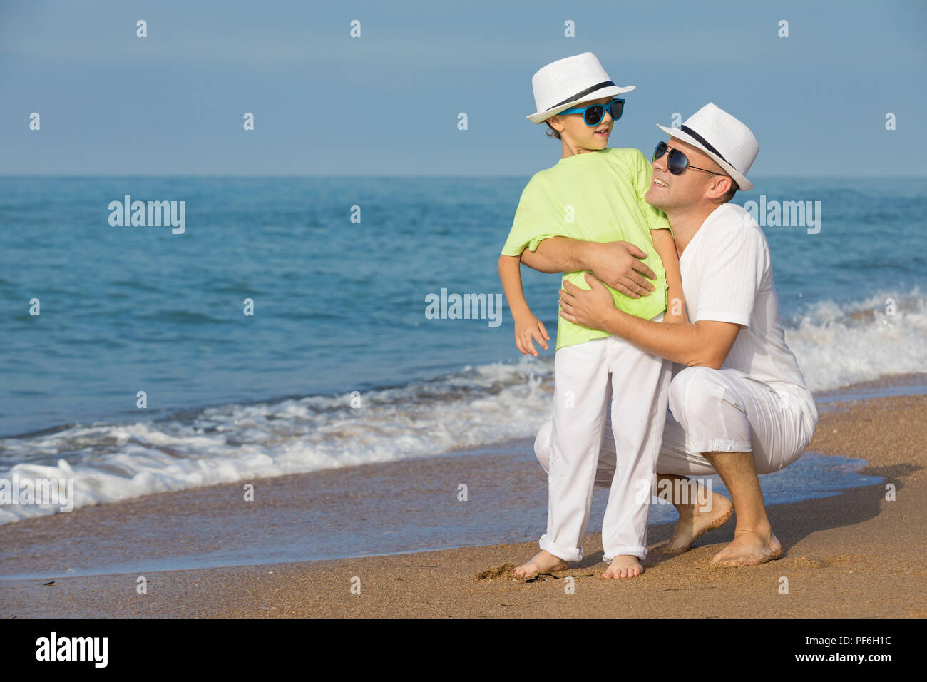 Father and son playing on the beach at the day time. People having fun outdoors. Concept of summer vacation and friendly family. Stock Photo