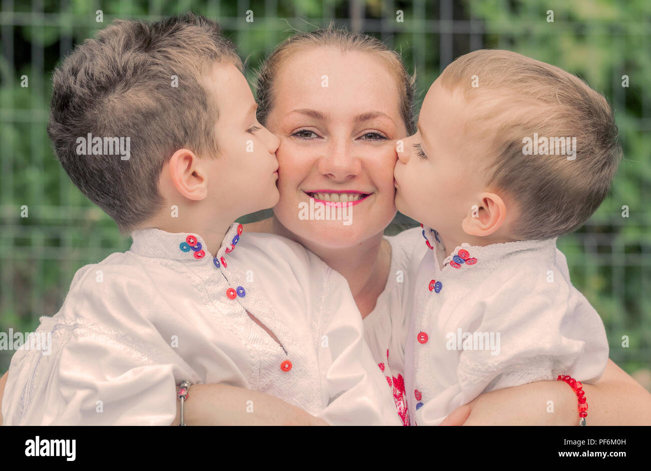 Happy young blonde mother cuddle with cheerful happy smiling sons children Stock Photo