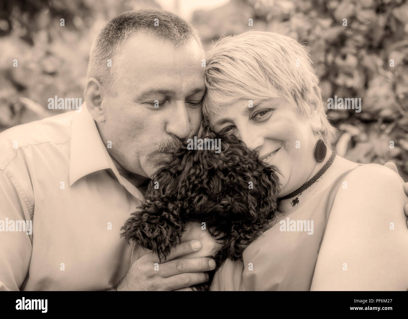 The beautiful romantic couple is having fun with their small dog Stock Photo