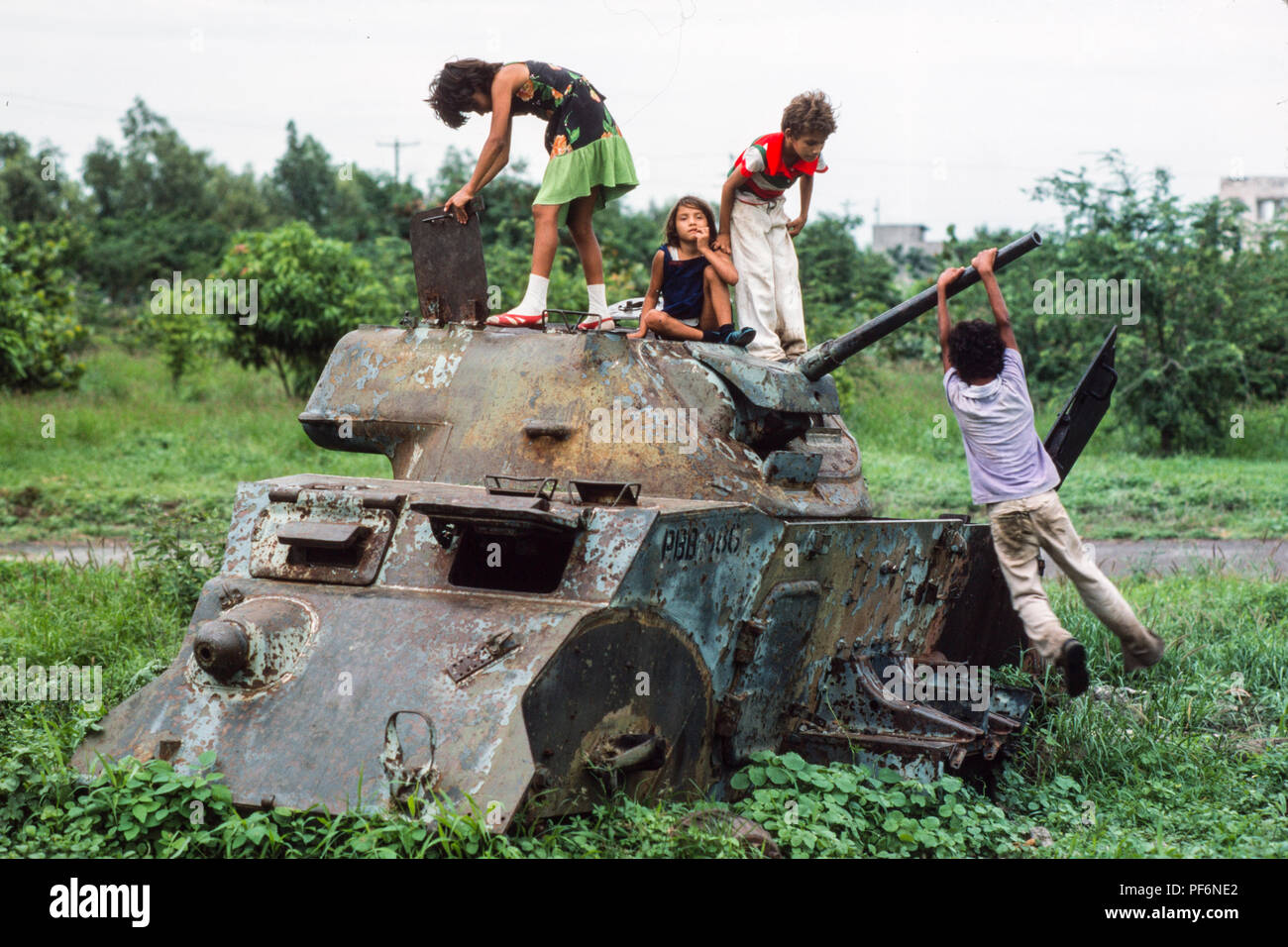 Managua, Nicaragua,  June 1986; Children play on the wrecked remains of Somoza's armoured tanks and APCs  in the centre of Managua. There were destryed by Sandinista forces in civil war against Somoza in 1979. Stock Photo