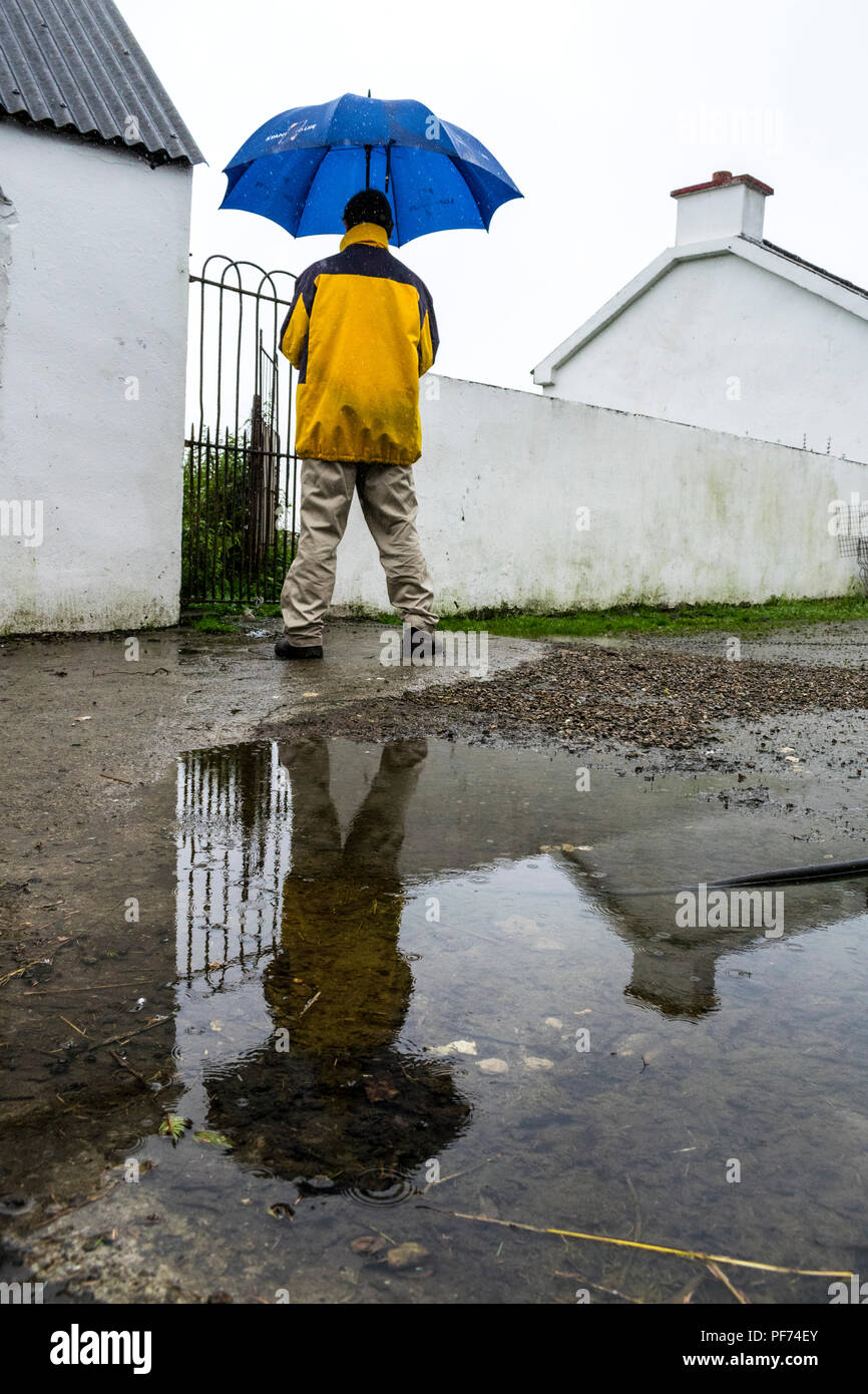 Ardara, County Donegal, Ireland weather. 20th August 2018.  A reflection of a man holding an umbrella in the rain on Ireland's north-west coast. Credit: Anna Hidalgo-Wayman/Alamy Live News Stock Photo