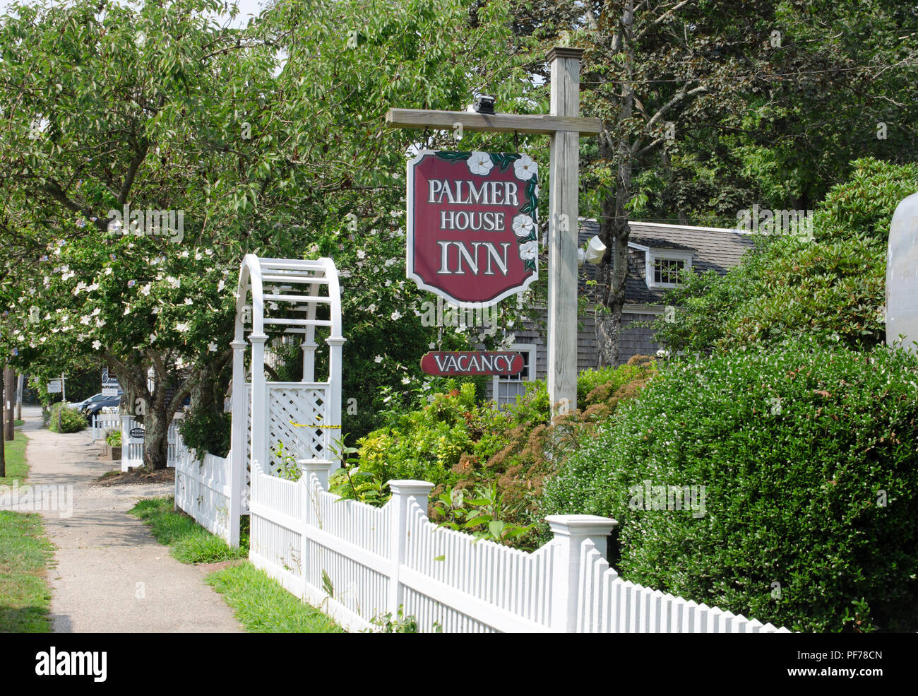 Tree lined street in Falmouth, Cape Cod, Massachusetts during summer with sign for the Palmer House Inn with vacancy, white picket fence and arbor Stock Photo