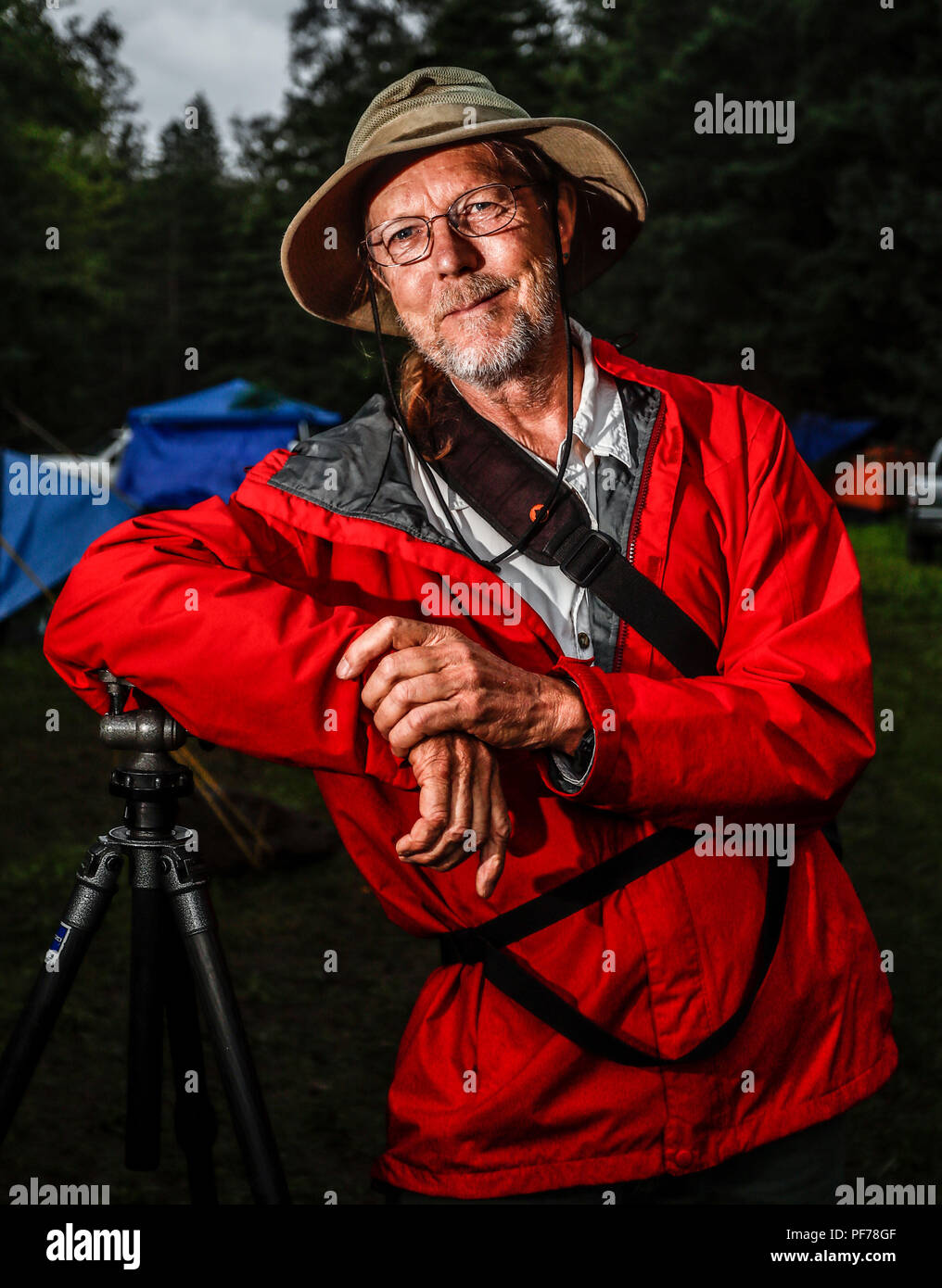 retrato del fotografo y biologo Chip Hedgcock recargado en su tripie. viste de sombrero, usa lentes e impermiable color rojo.    portrait of the photographer and biologist Chip Hedgcock recharged in his tripie. wear a hat, wear glasses and an impervious red color.  https://www.charleshedgcock.com  Charles 'Chip' Hedgcock has combined his love of the outdoors with more than 25 years of experience photographing in medicine, the life sciences, and fine arts, to create a unique vision of the natural world. Whether he is chasing fringe-toed lizards over remote sand dunes in the summer heat or, ligh Stock Photo