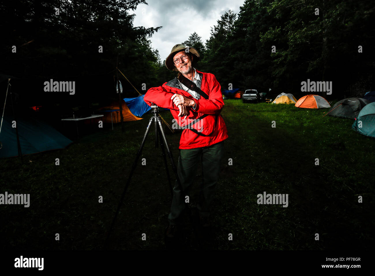 retrato del fotografo y biologo Chip Hedgcock recargado en su tripie. viste de sombrero, usa lentes e impermiable color rojo.    portrait of the photographer and biologist Chip Hedgcock recharged in his tripie. wear a hat, wear glasses and an impervious red color.  https://www.charleshedgcock.com  Charles 'Chip' Hedgcock has combined his love of the outdoors with more than 25 years of experience photographing in medicine, the life sciences, and fine arts, to create a unique vision of the natural world. Whether he is chasing fringe-toed lizards over remote sand dunes in the summer heat or, ligh Stock Photo