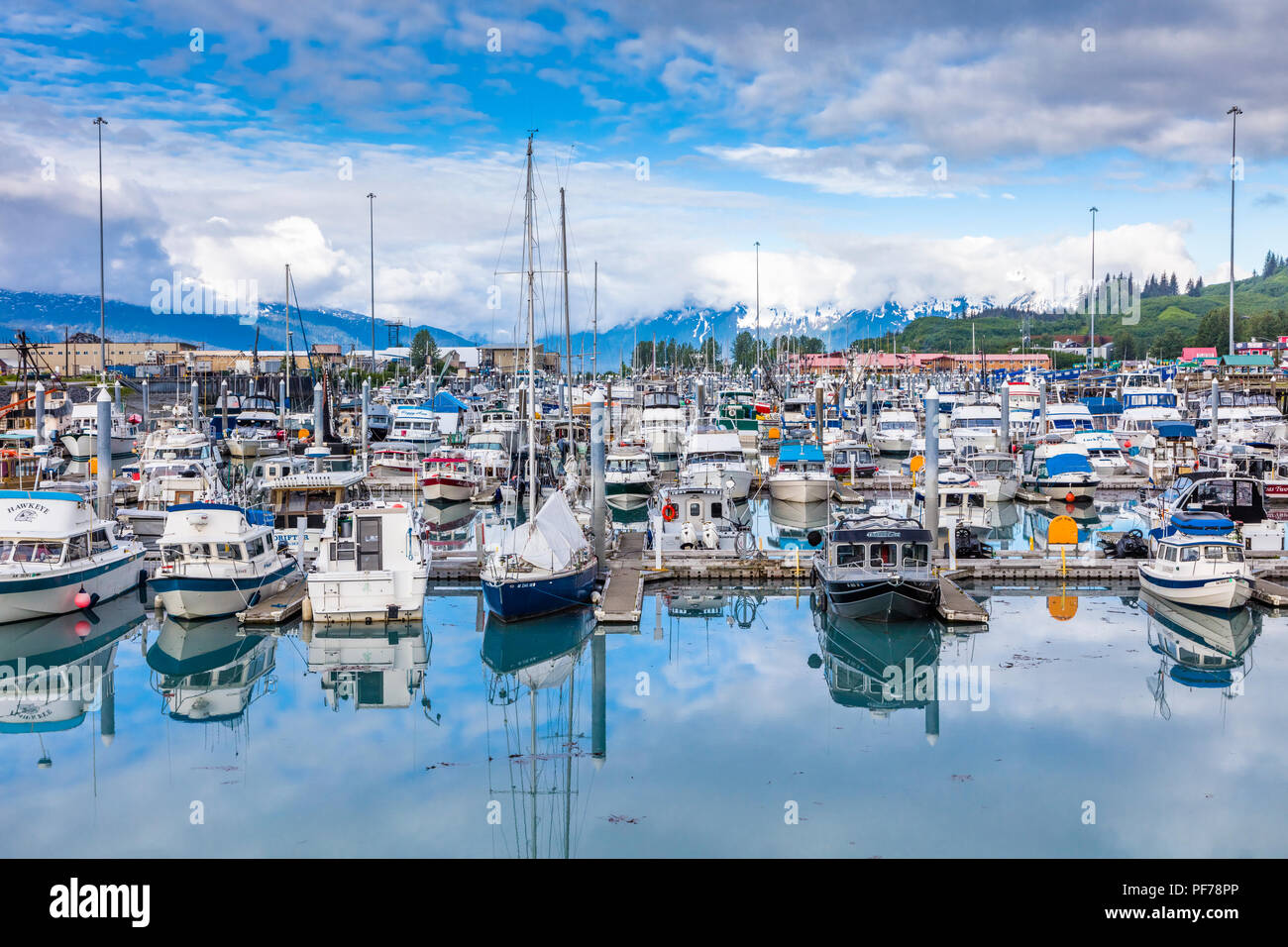 Big white clouds with patches of blue sky over small boat harbor on Prince William Sound in Valdez Alaska Stock Photo