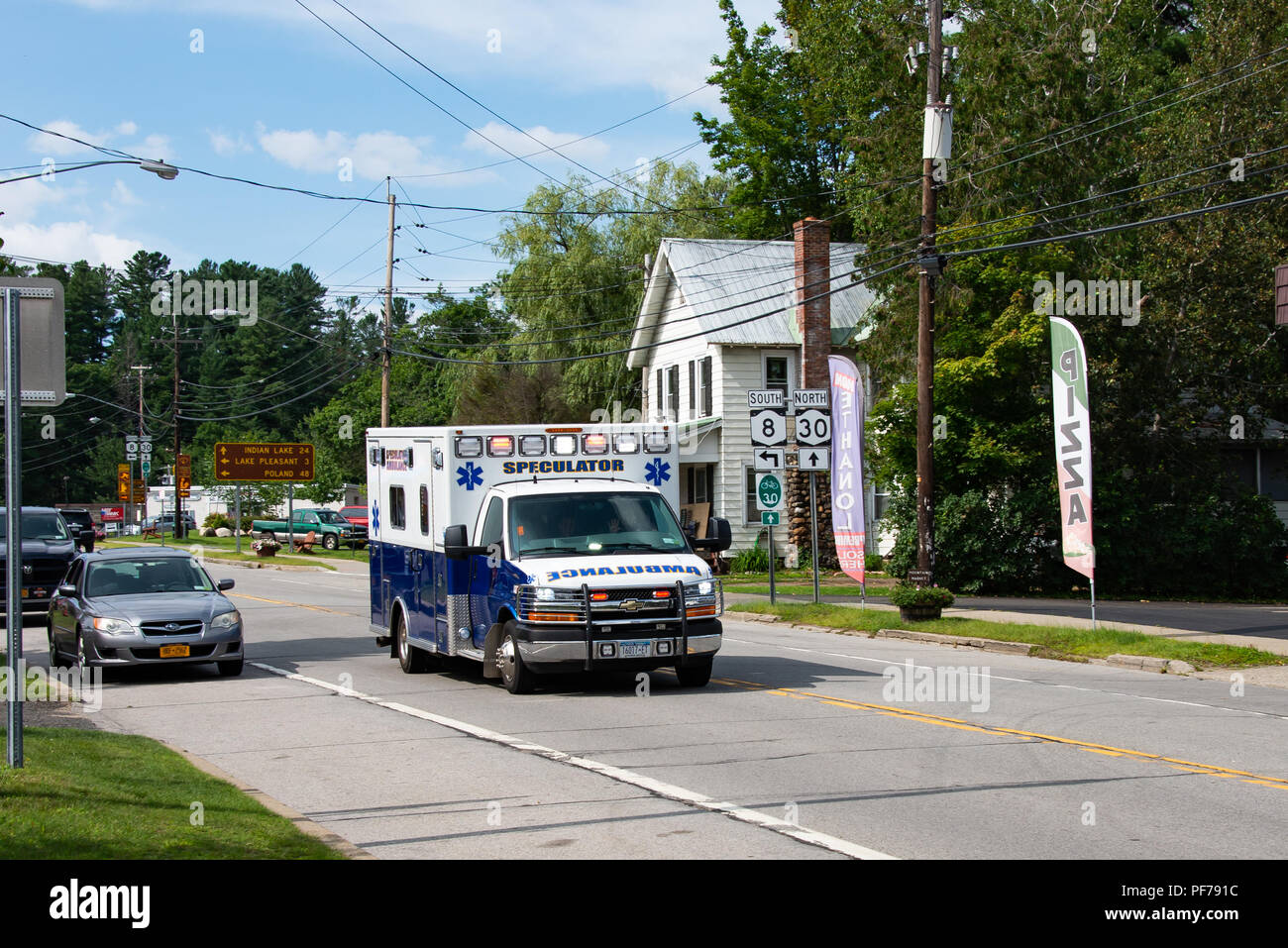 The Speculator ambulance racing through Speculator, NY USA responding to an emergency with lights flashing. Stock Photo