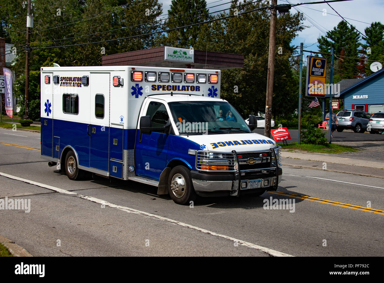 The Speculator ambulance racing through Speculator, NY USA responding to an emergency with lights flashing. Stock Photo