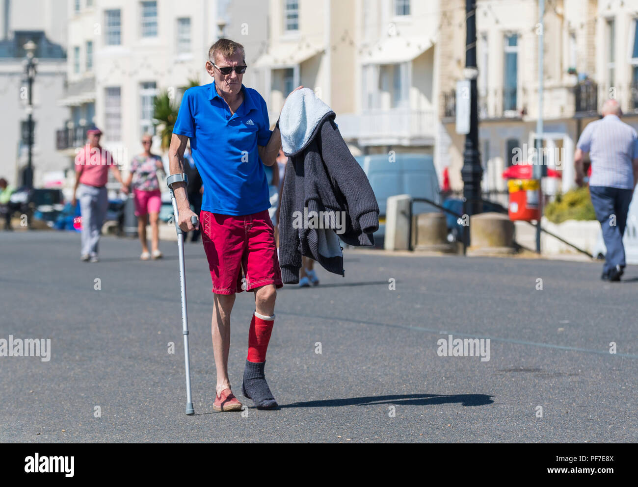 Man with injured leg walking with the aid of a crutch. Man walking with crutches. Stock Photo