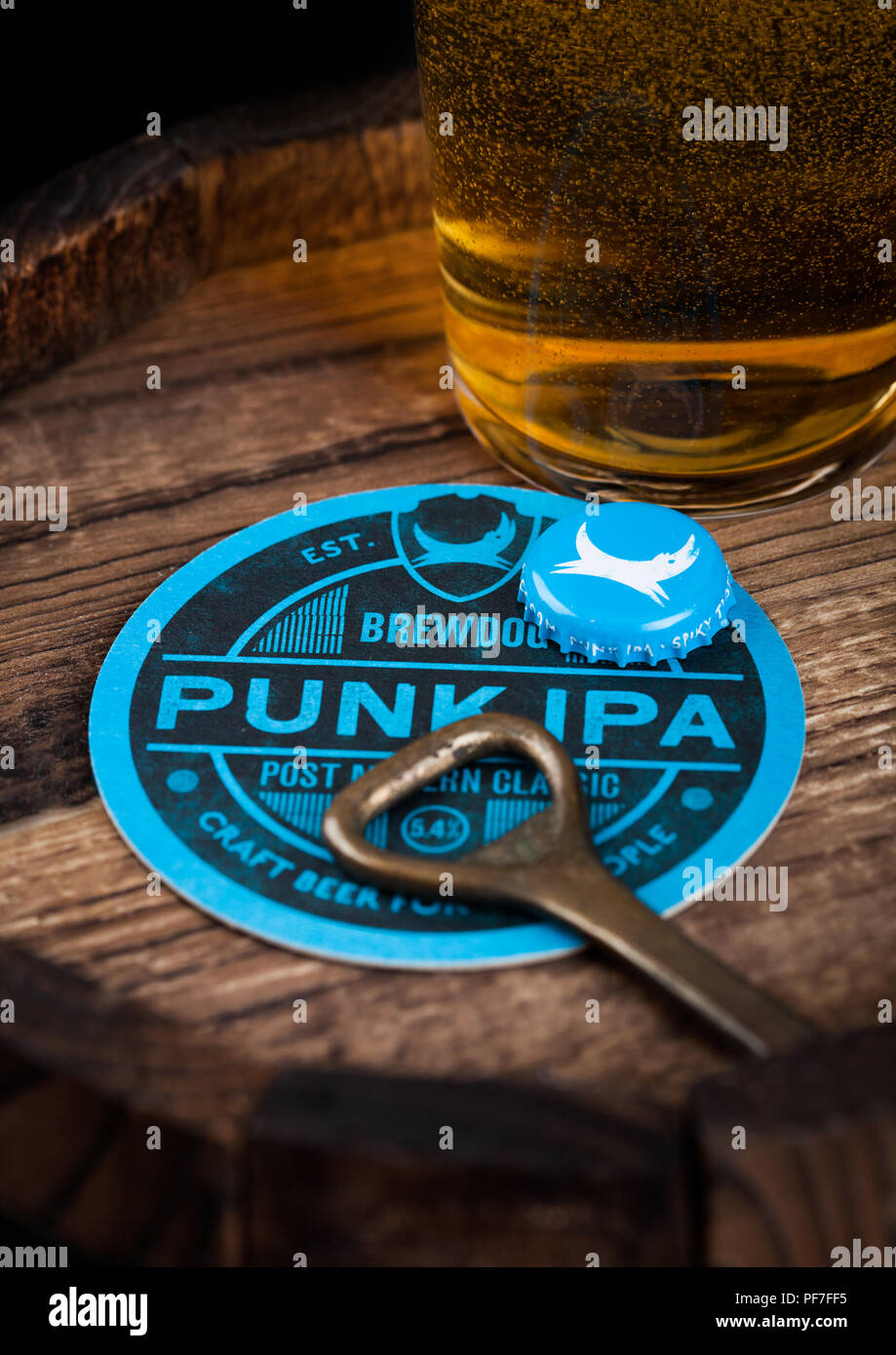 LONDON, UK - AUGUST 10, 2018: Brewdog Punk Ipa beer coaster with bottle top and opener and glass of beer on top of wood barrel. Stock Photo