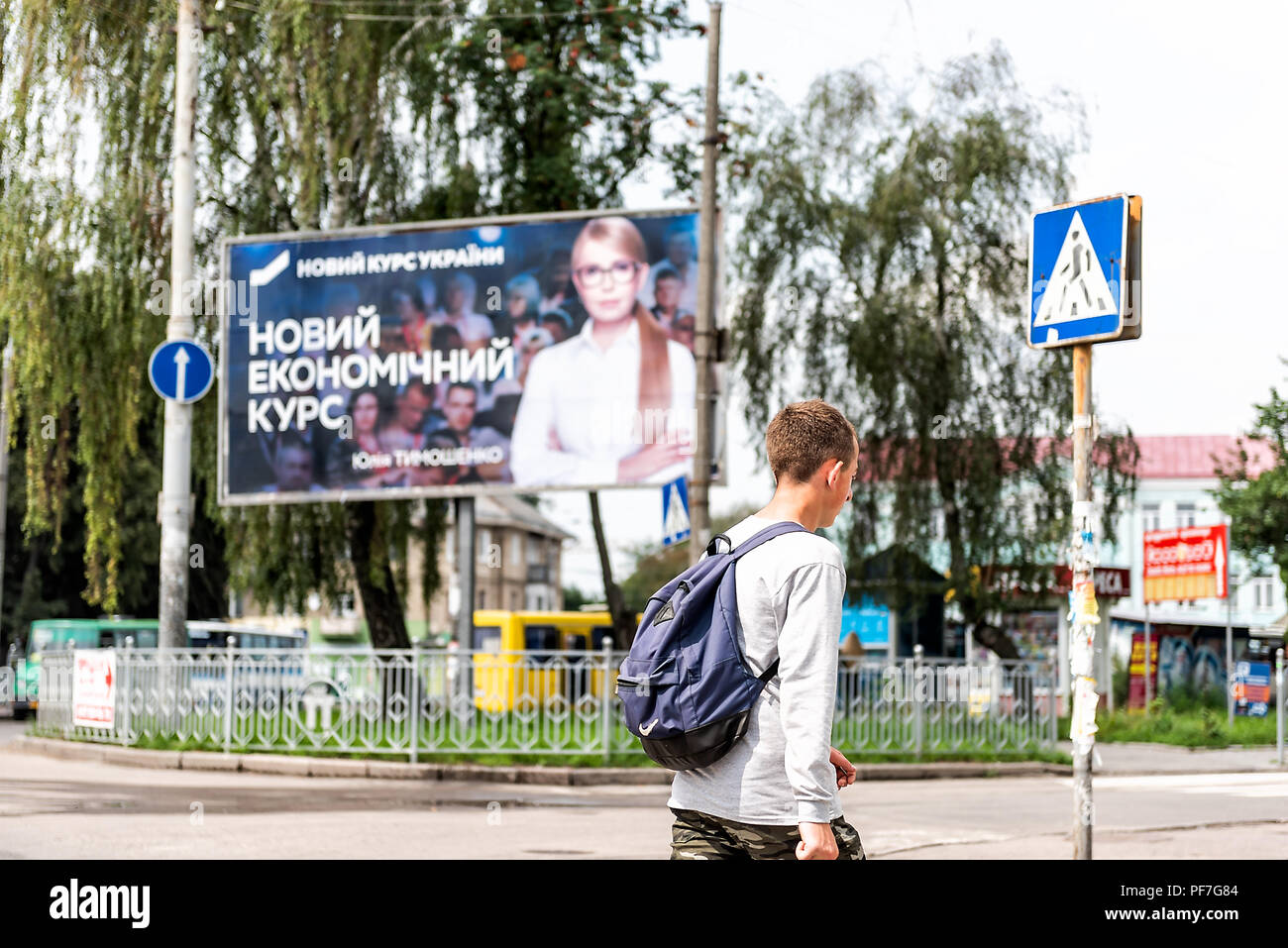 Rivne, Ukraine - July 28, 2018: Young Ukrainian man walking in front of political advertisement ad banner sign, Yulia Tymoshenko for president by stre Stock Photo