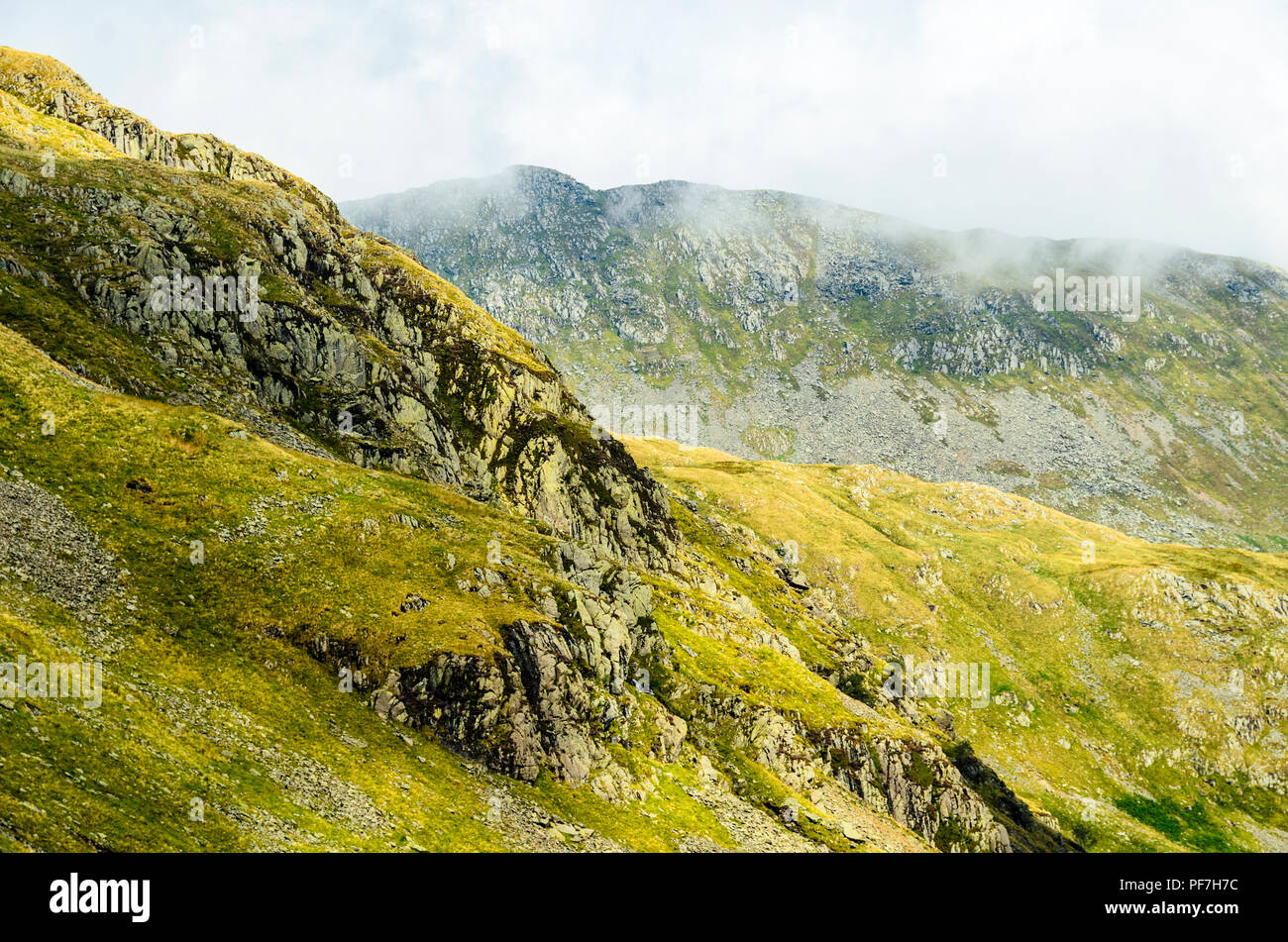 Upper slopes of Eagle Crag above Grisedale in the Lake District with Striding Edge in mist behind Stock Photo