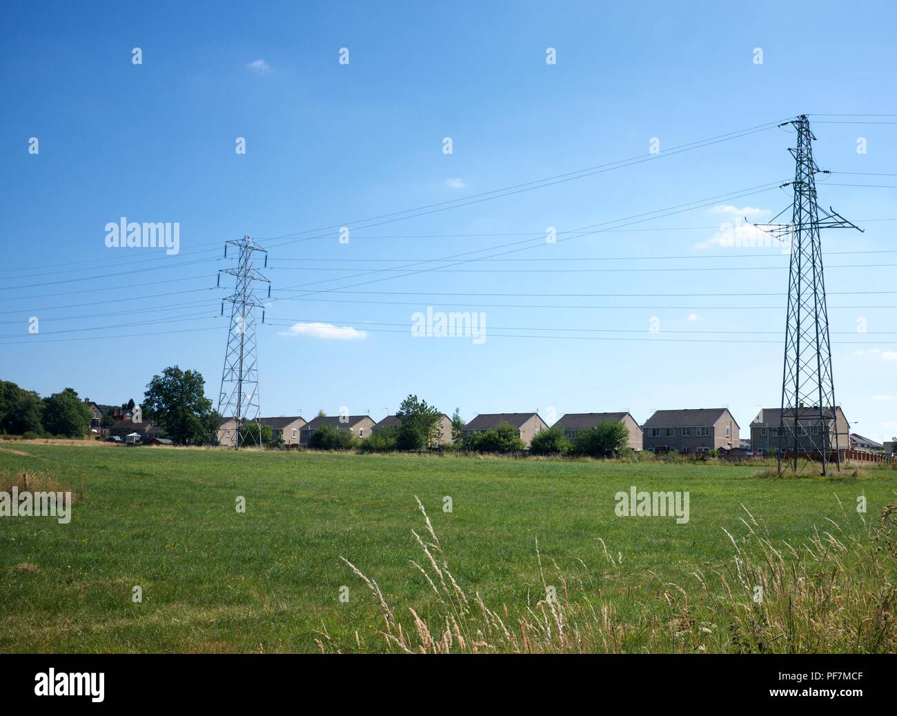 Pylons tower over a housing estate in New Mills,  High Peak,  Derbyshire Stock Photo