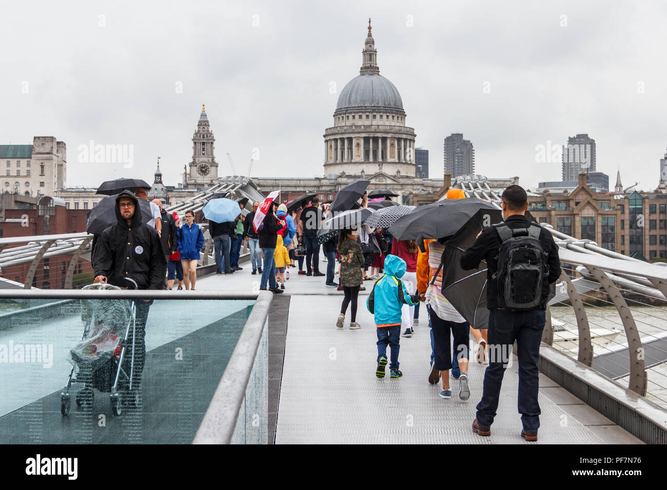 Sightseers with umbrellas battling blustery rain on the Millennium