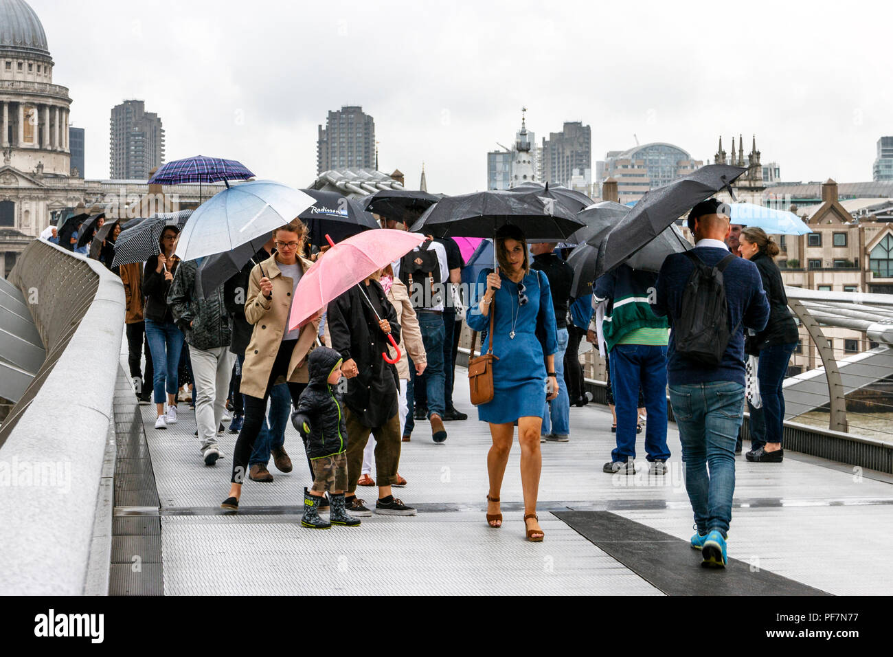 Sightseers with umbrellas battling blustery rain on the Millennium