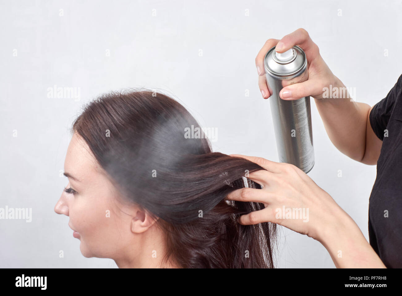 Female hairdresser makes a haircut with aerosol for a woman closeup in beauty salon Stock Photo