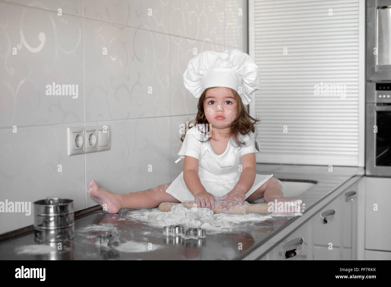 Little girl making dough and cookies in kitchen Stock Photo