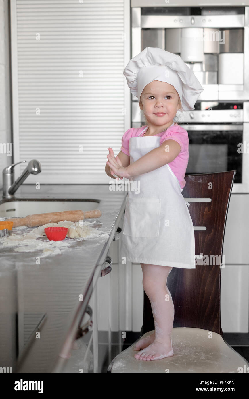 beautiful little girl learns to cook a meal in the kitchen Stock Photo