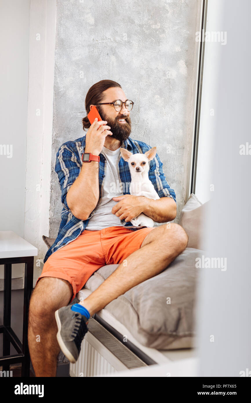 Handsome man laughing while speaking by the phone Stock Photo