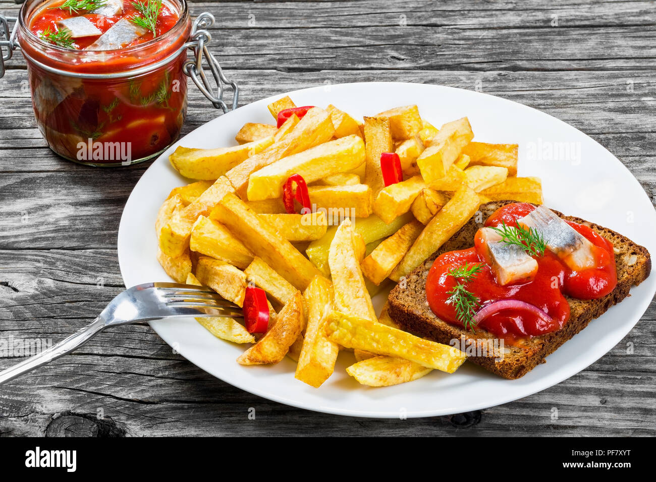 Potato Fries with pieces of chili pepper on a white dish and Slices of  marinated Norwegian herring in tomato sauce on the pieces of rye bread, a  glass Stock Photo - Alamy