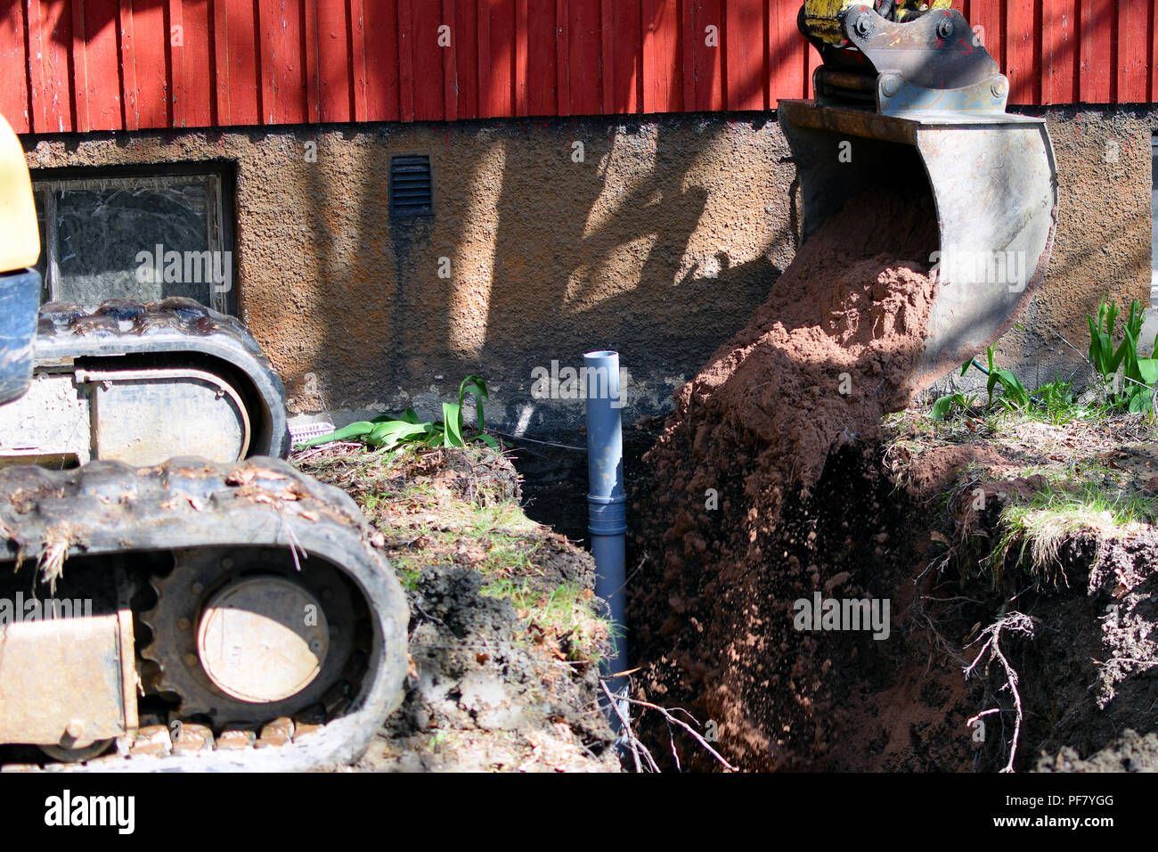 Excavator in construction site filling the sewer pipe trench with sand. Stock Photo