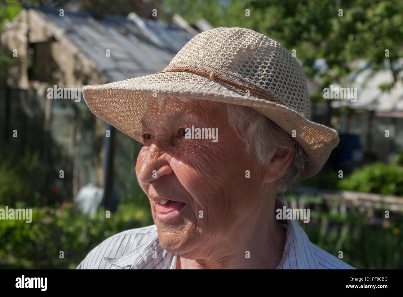 Happy older woman with straw hat in her garden Stock Photo - Alamy