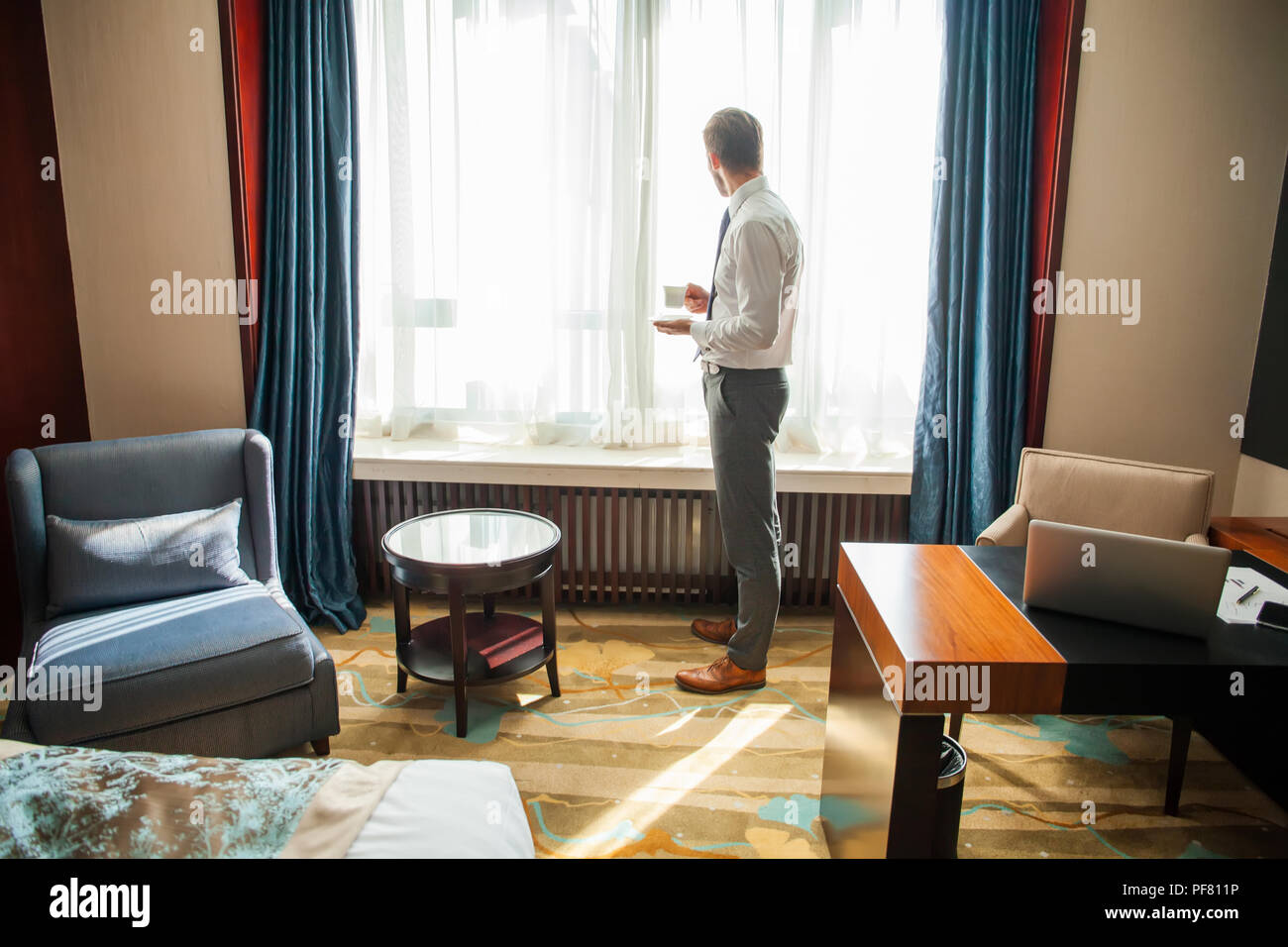 business trip and people concept - businessman drinking coffee at hotel room. Stock Photo