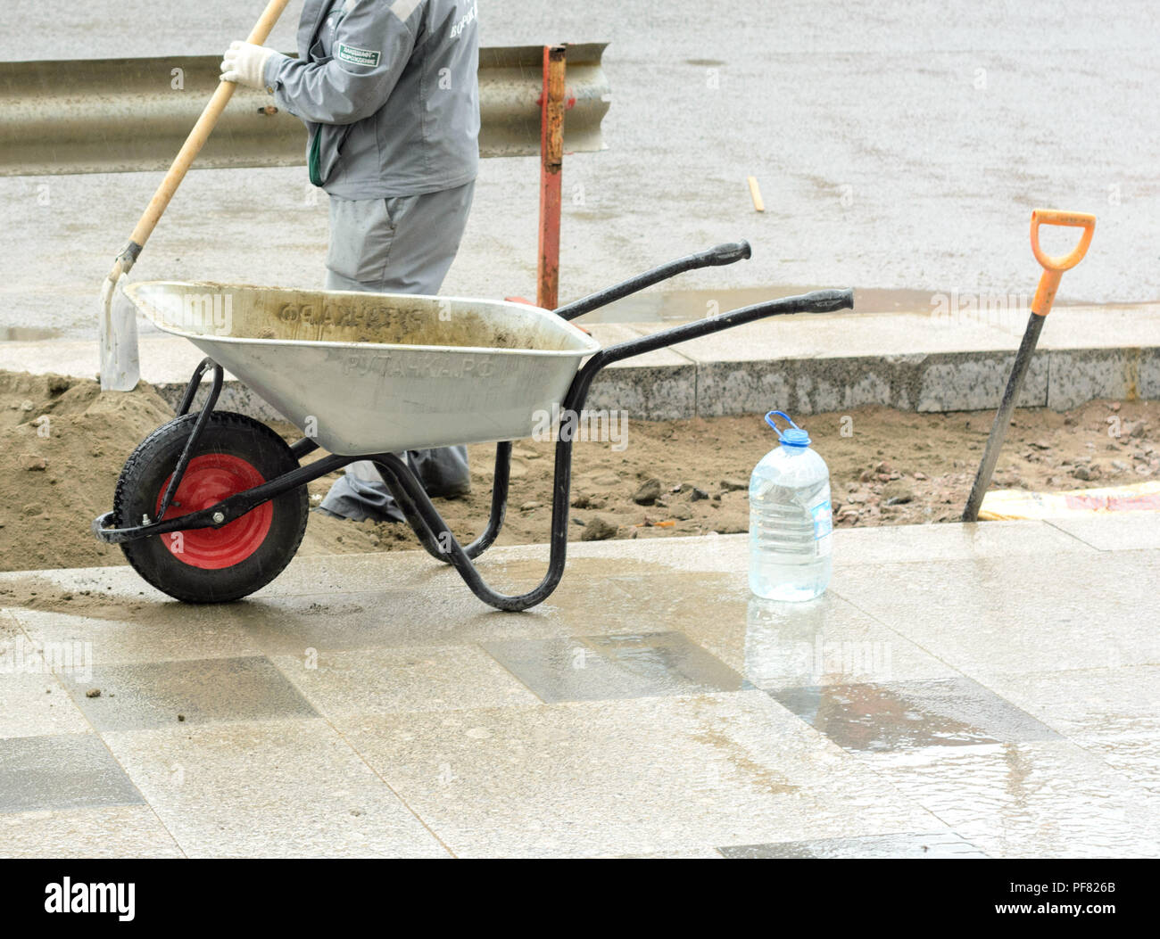 The worker brings on a construction wheelbarrow sand for laying paving slabs on the street. Stock Photo