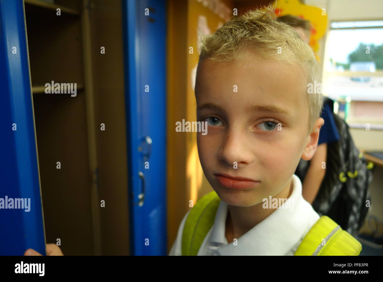 Back to school for elementary aged boy, putting his backpack in his locker Stock Photo