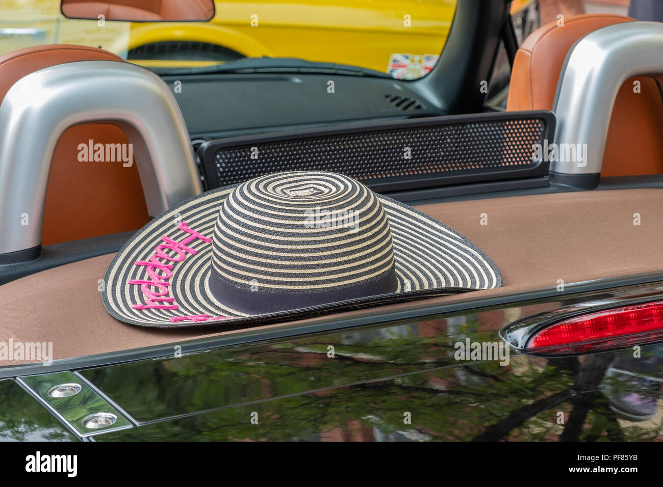 Straw hat sitting on the back deck of a convertible.  Can be used mutiple ways to convey a concept such as travel, lifestyle, leisure, and retirement. Stock Photo