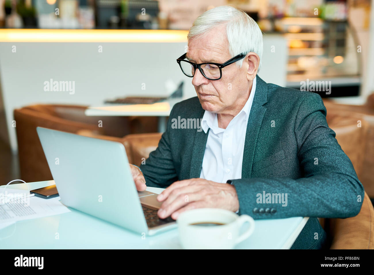 Senior Businessman Using Laptop in Cafe Stock Photo