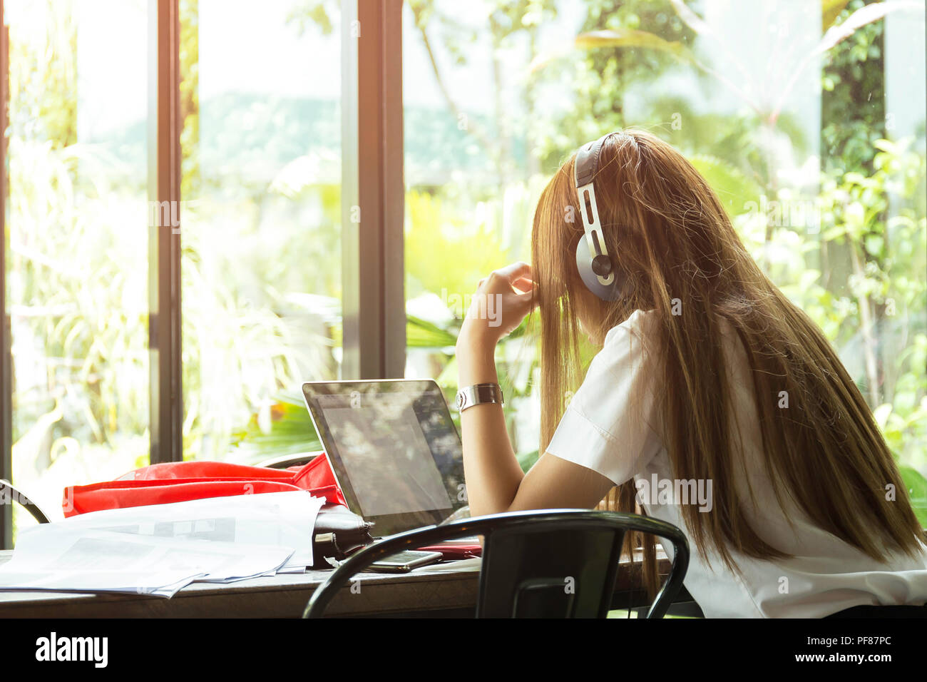 Asian students in uniform with headphone studying in coffee shop using laptop computer Stock Photo