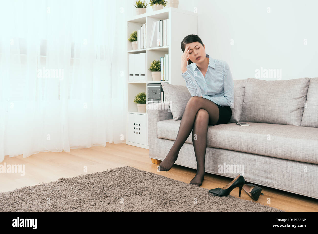 business girl feel headache sitting on the sofa in the living room at home Stock Photo