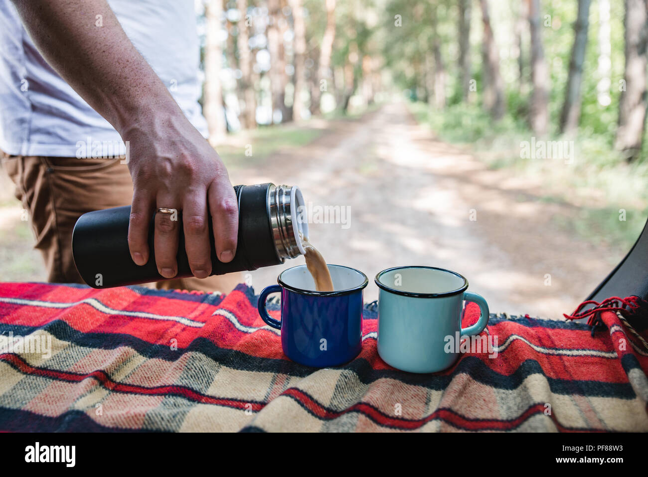 man hand pour on coffee into metal cups from thermos bottle. copy space Stock Photo