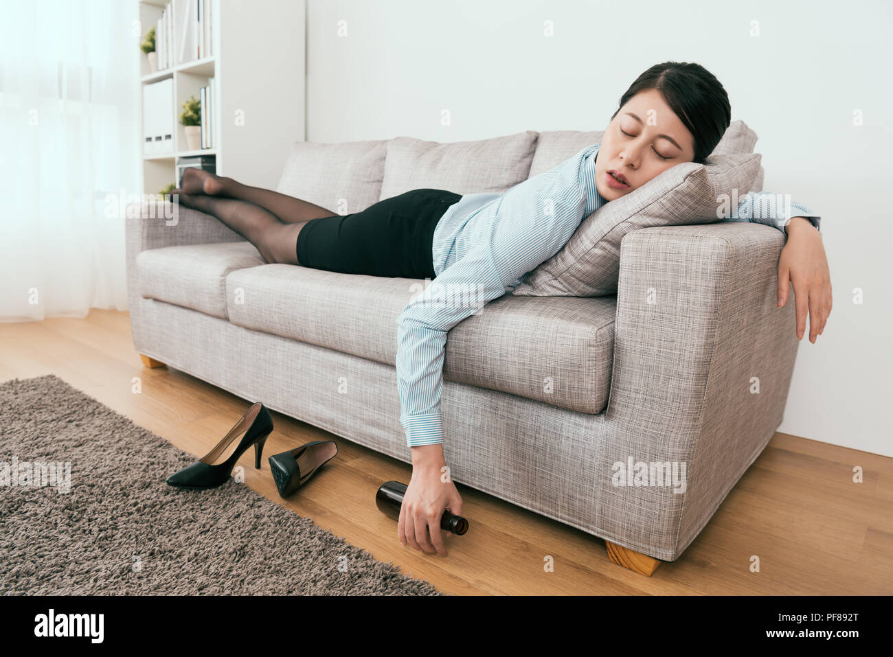 she is drunk and fell asleep on the sofa in the living room at home Stock Photo