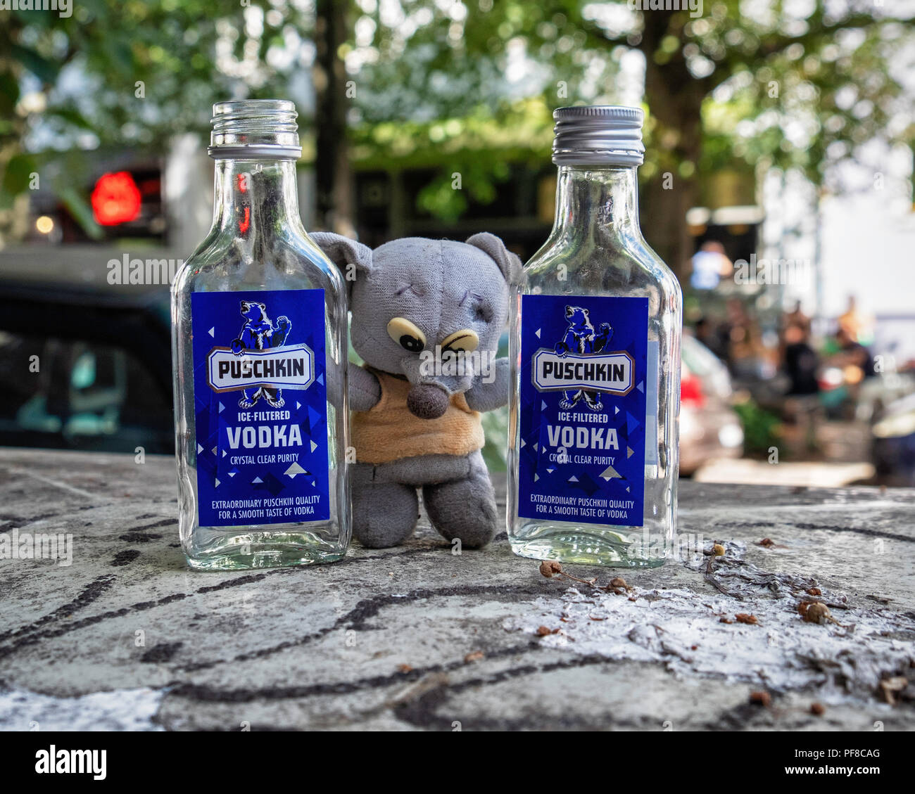 Urban Still life - Small fluffy toy and two empty vodka bottles on a city bin..child's toy misplaced, lost or abandoned? Stock Photo