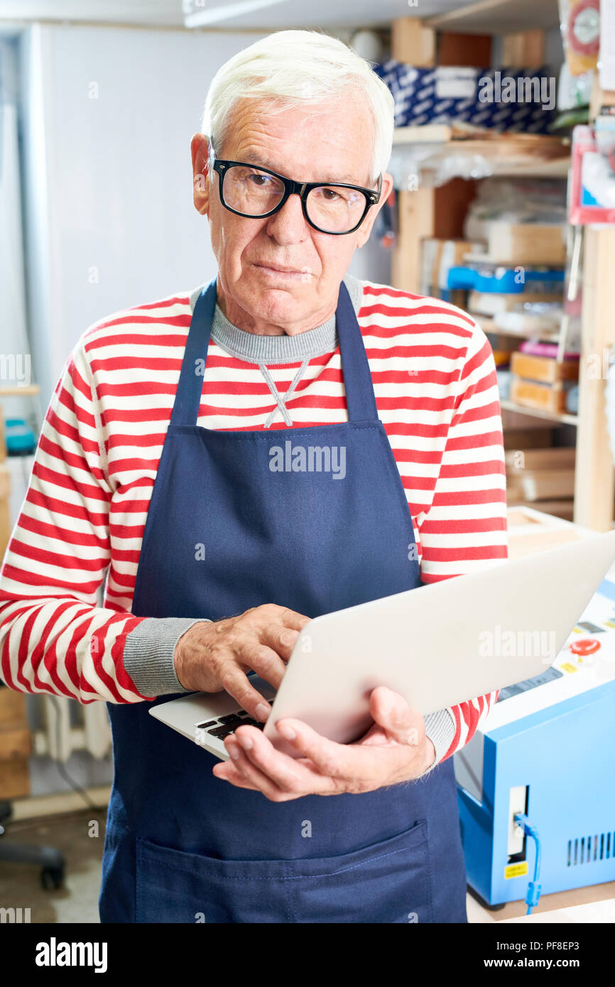 Senior craftsman browsing modern laptop Stock Photo
