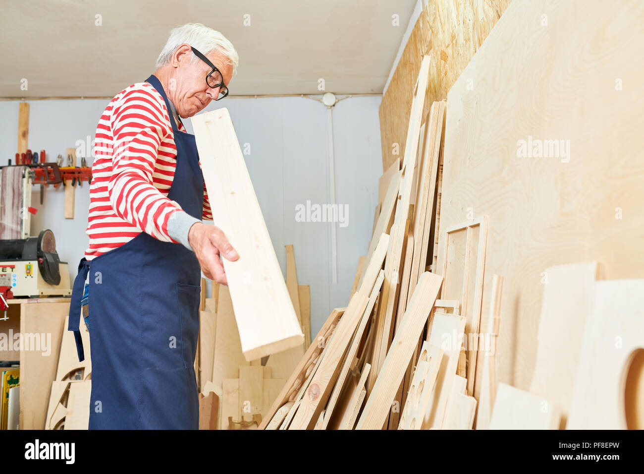 Aged carpenter looking at wooden plank Stock Photo