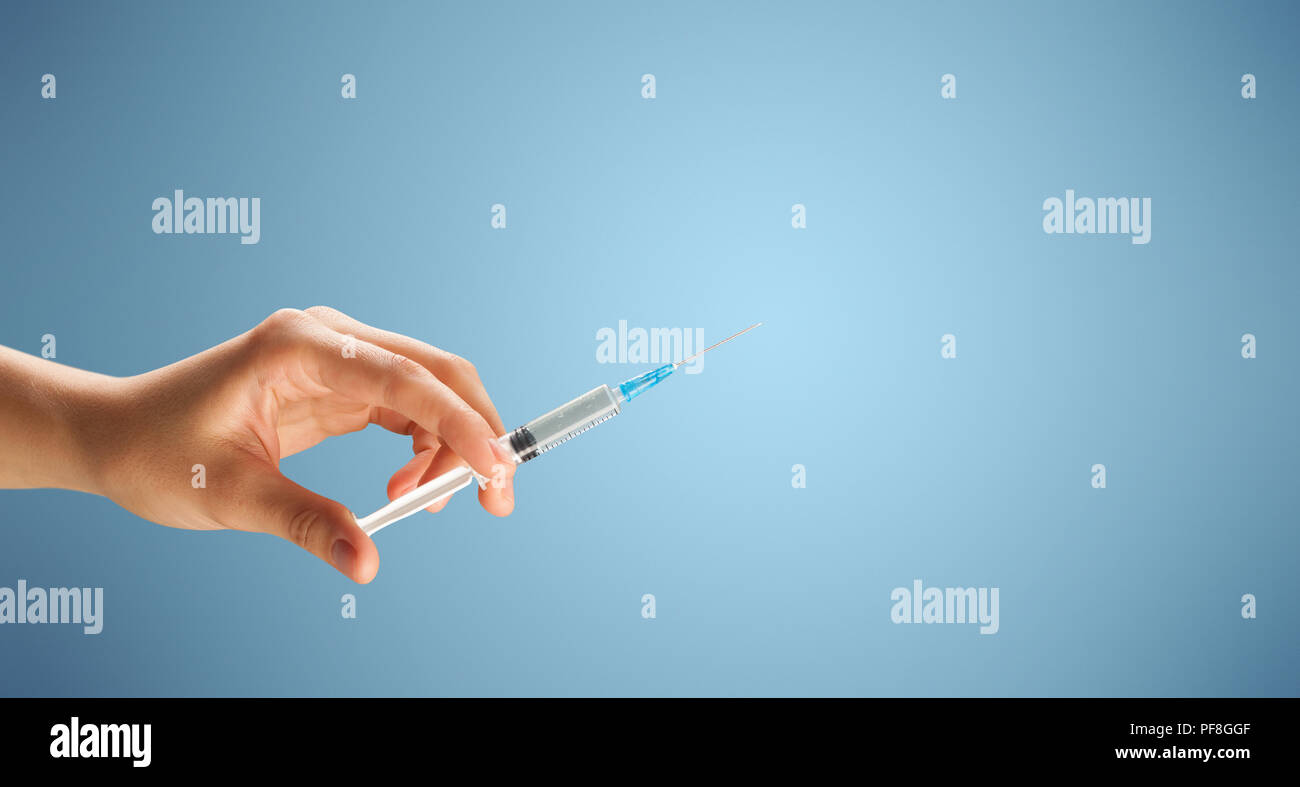 Female doctor hand holding syringe with blue background Stock Photo - Alamy